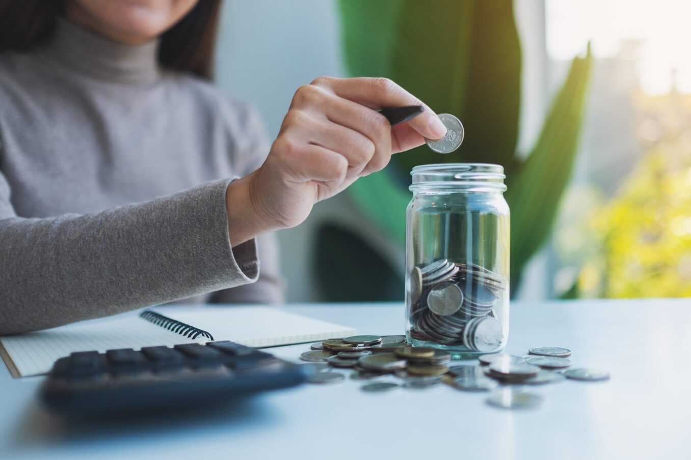A closeup of a woman inserting coins into a jar
