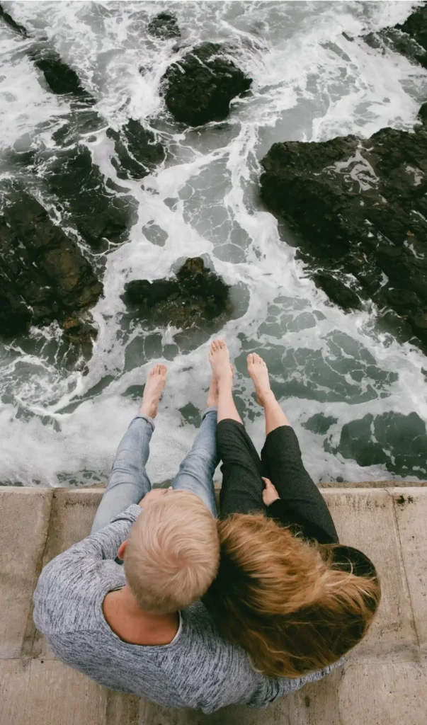 Couple sitting on ledge looking over ocean