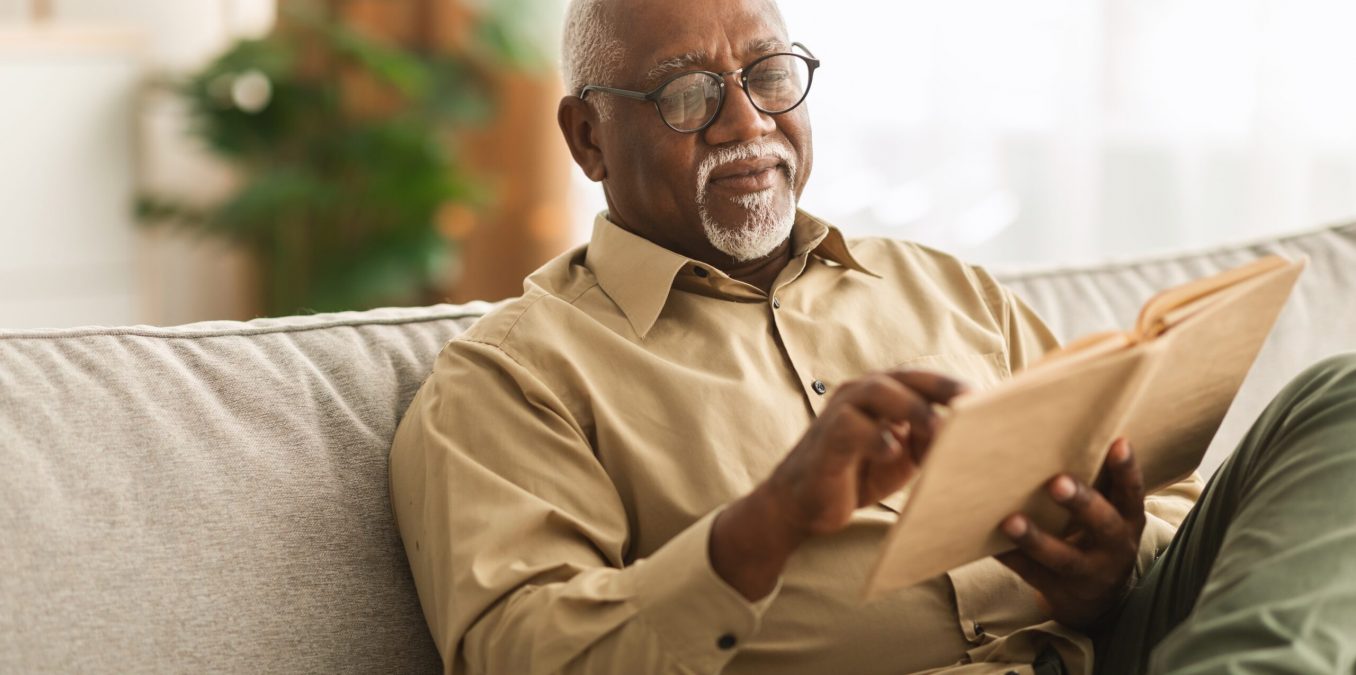 Senior,African,American,Man,Reading,Book,Sitting,On,Couch,At
