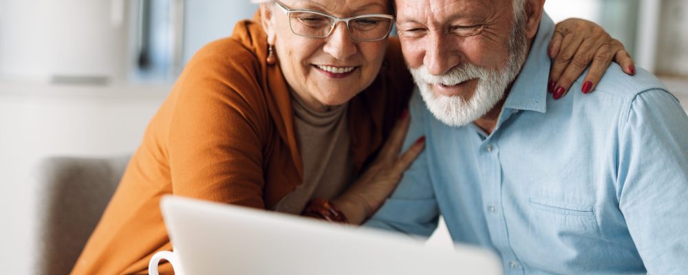Embraced,Senior,Couple,Using,Laptop,At,Home