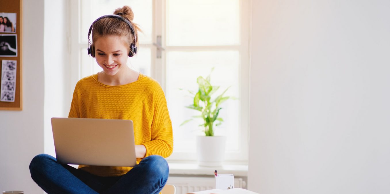 A,Young,Female,Student,Sitting,At,The,Table,,Using,Headphones