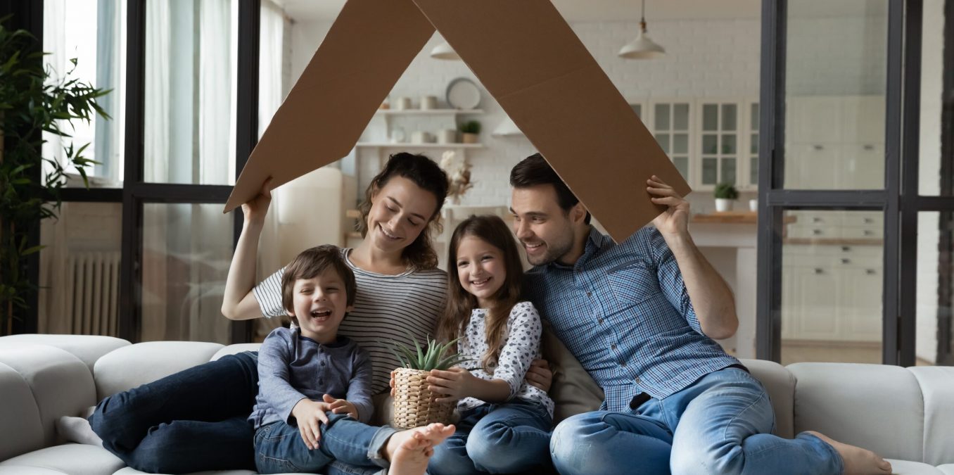 Happy,Sibling,Kids,And,Parents,Holding,Carton,Toy,Roof,Above