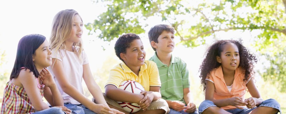 Five,Young,Friends,Sitting,Outdoors,With,Soccer,Ball