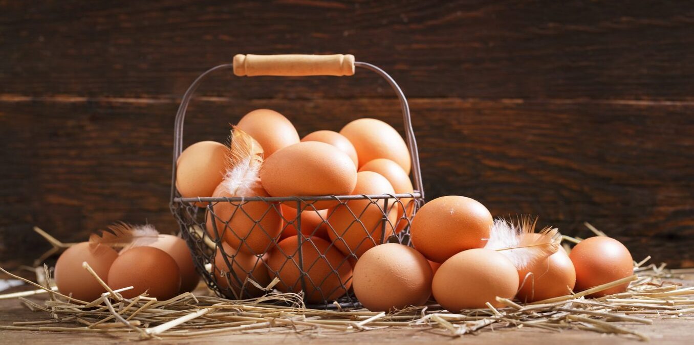 basket of fresh chicken eggs on a wooden background