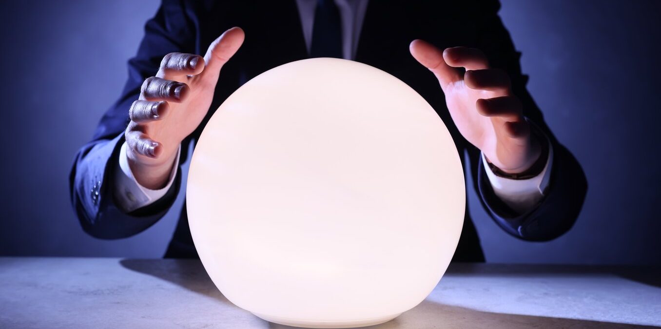 Businessman using glowing crystal ball to predict future at table, closeup