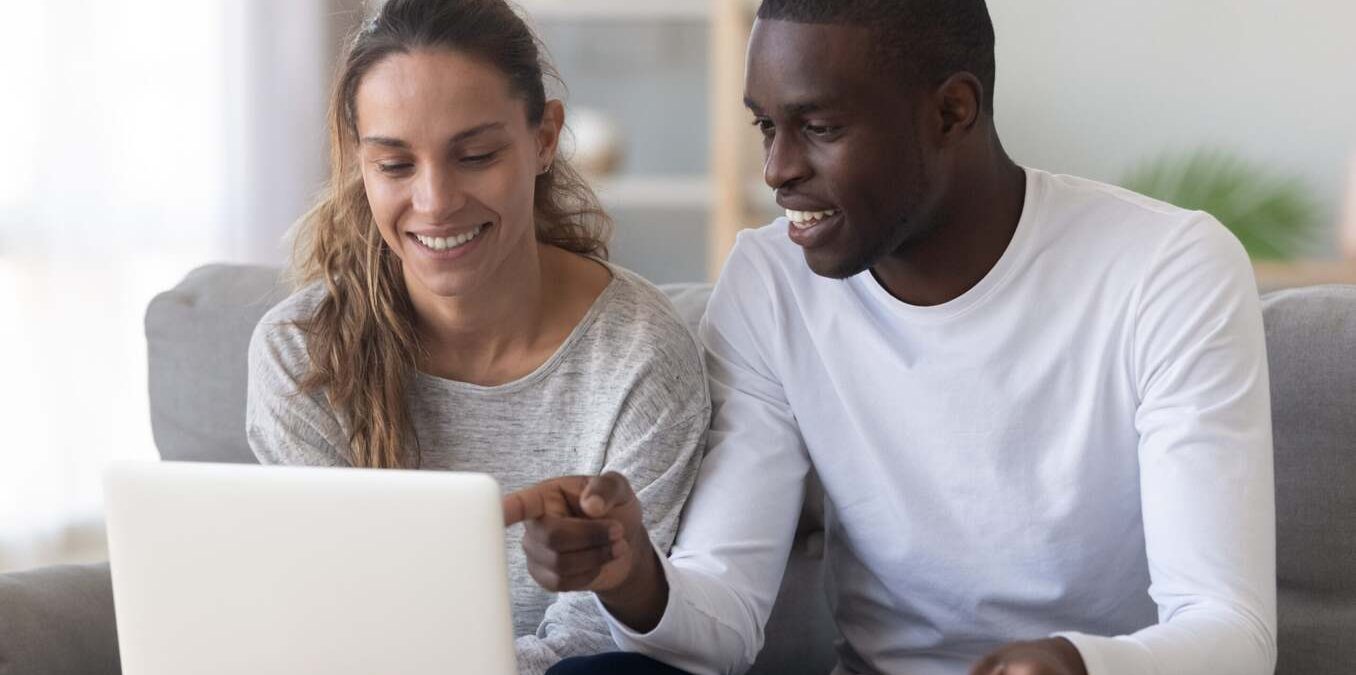 Laughing couple looking at a computer screen at home