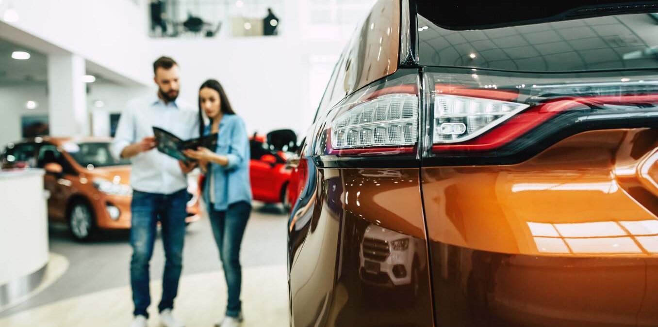 Couple looking to buy a car at a dealership. Close-up of the car headlight