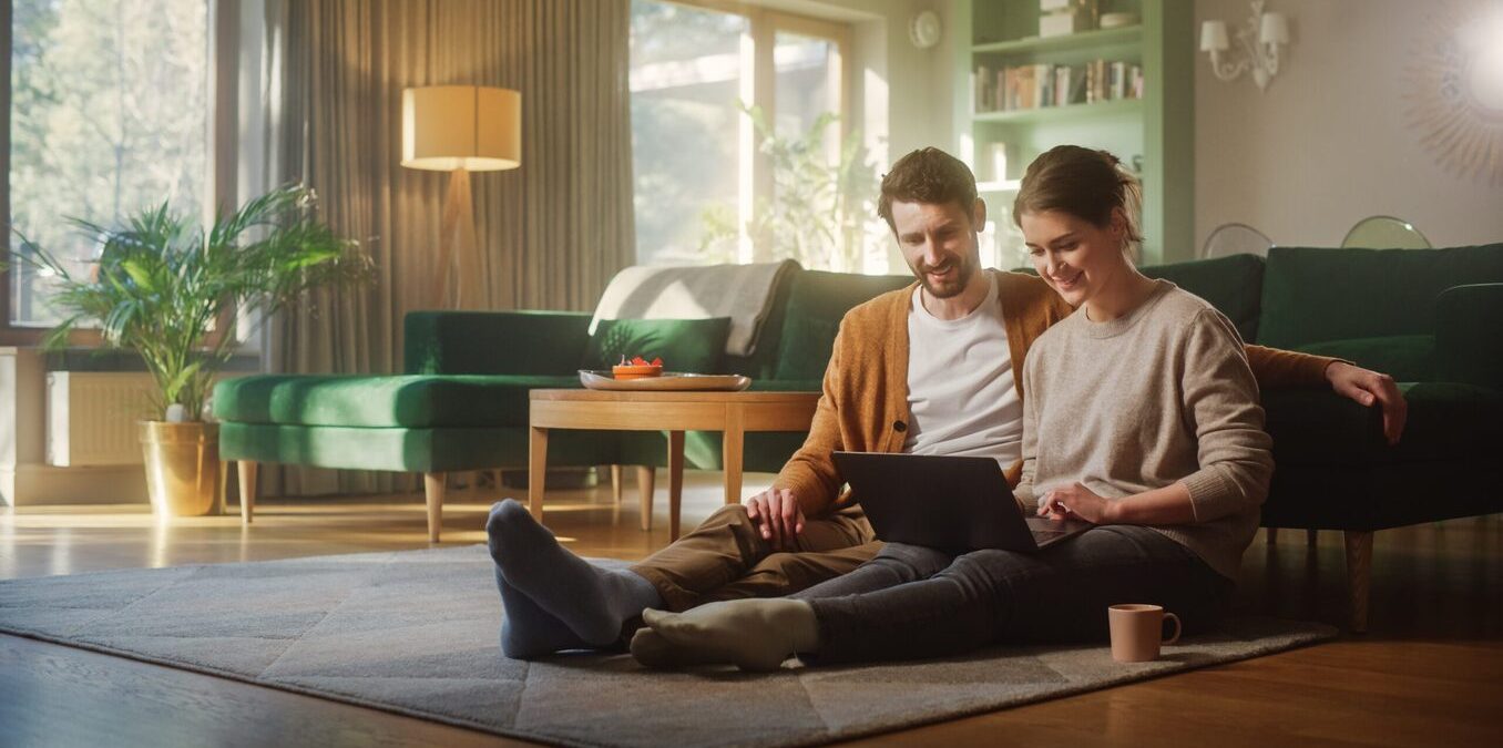 Couple Use Laptop Computer, while sitting on the living floor room of their apartment