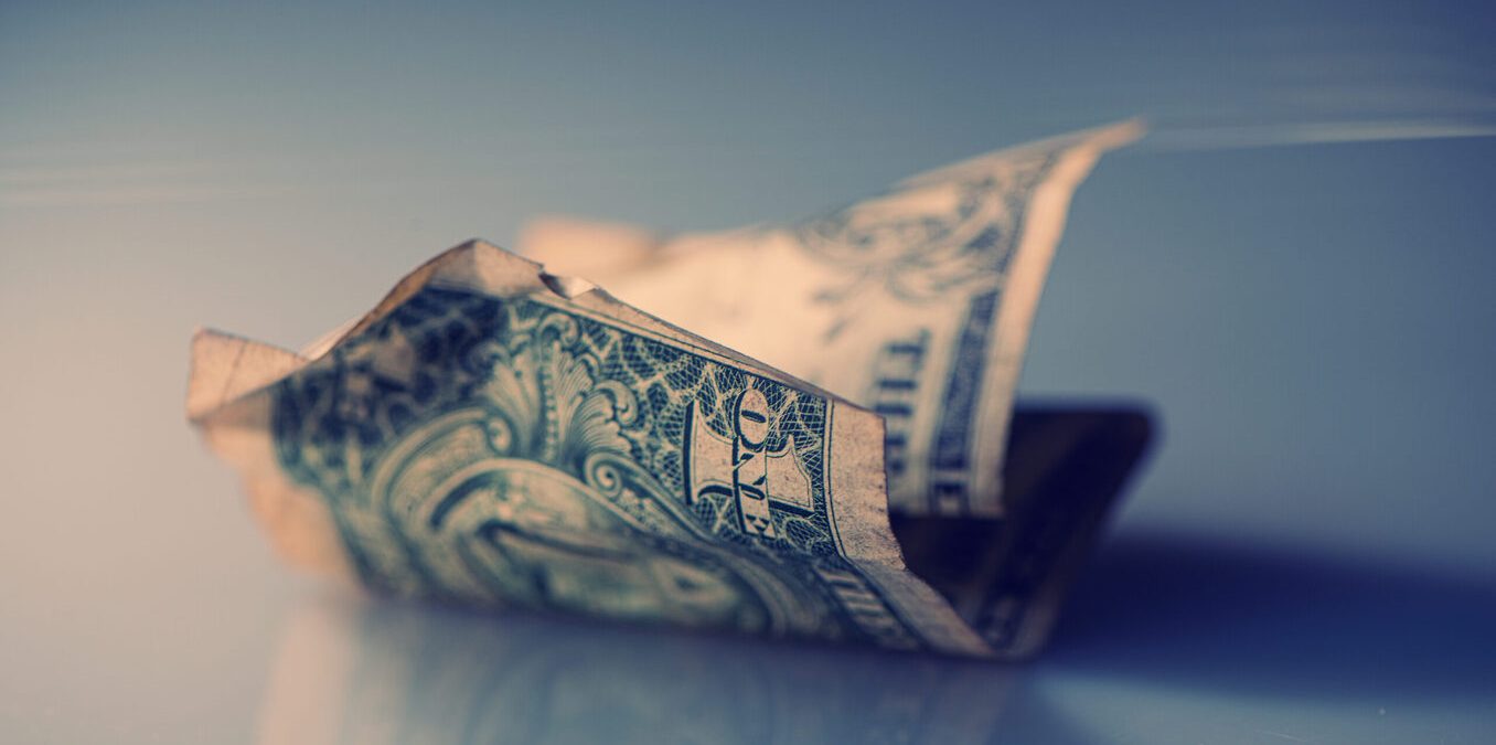 Crumpled dollar bill on reflective surface