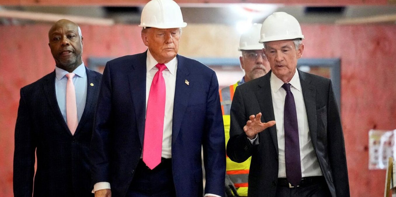 Donald Trump and Jerome Powell wearing white hard hats while walking through a construction site and engaging in conversation.