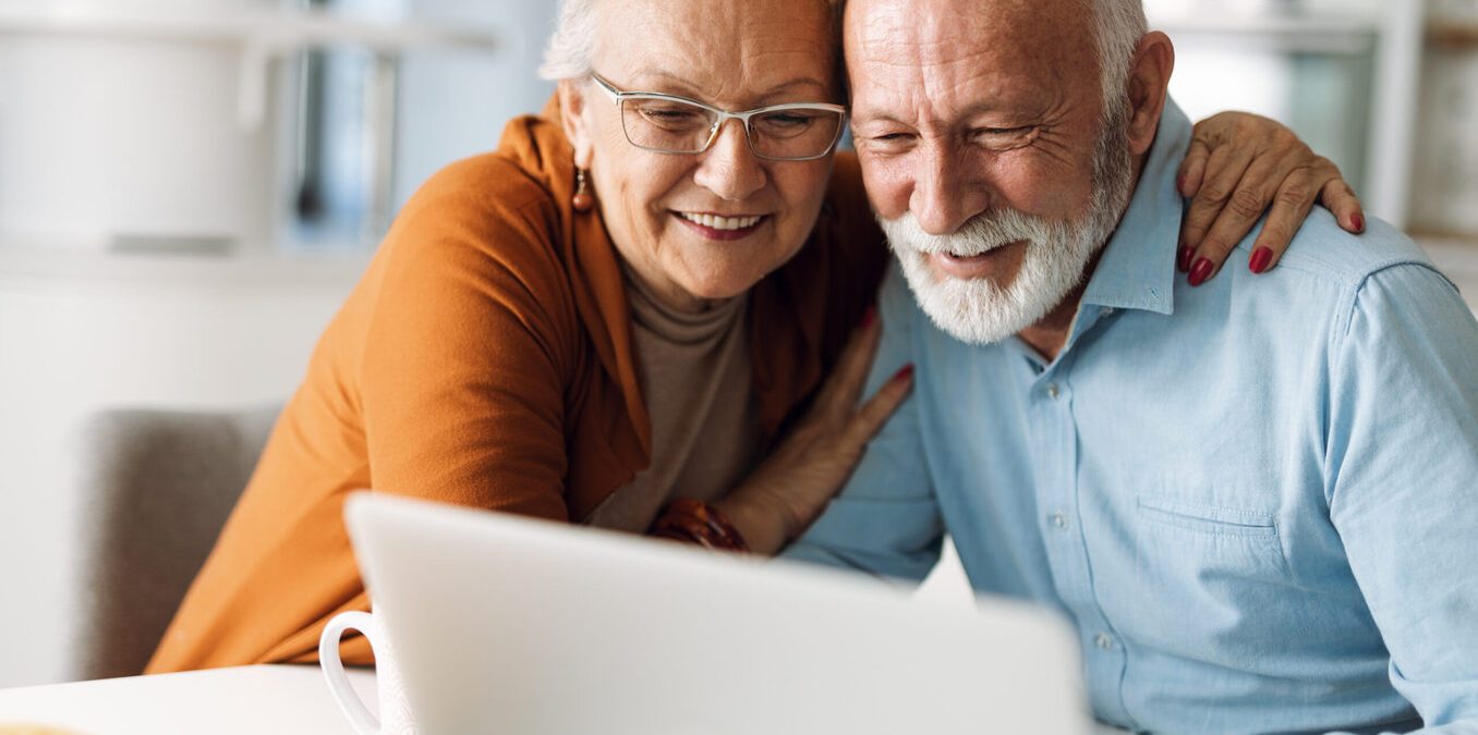 Elderly couple hugging and looking at a computer
