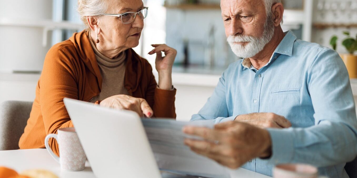 Elderly couple reviewing documents in front of a computer