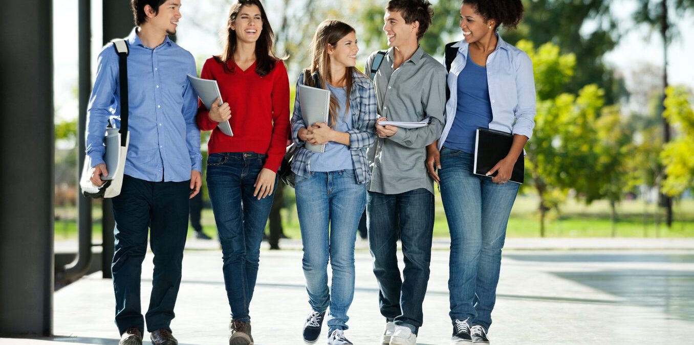 Full length of happy college students walking together on campus