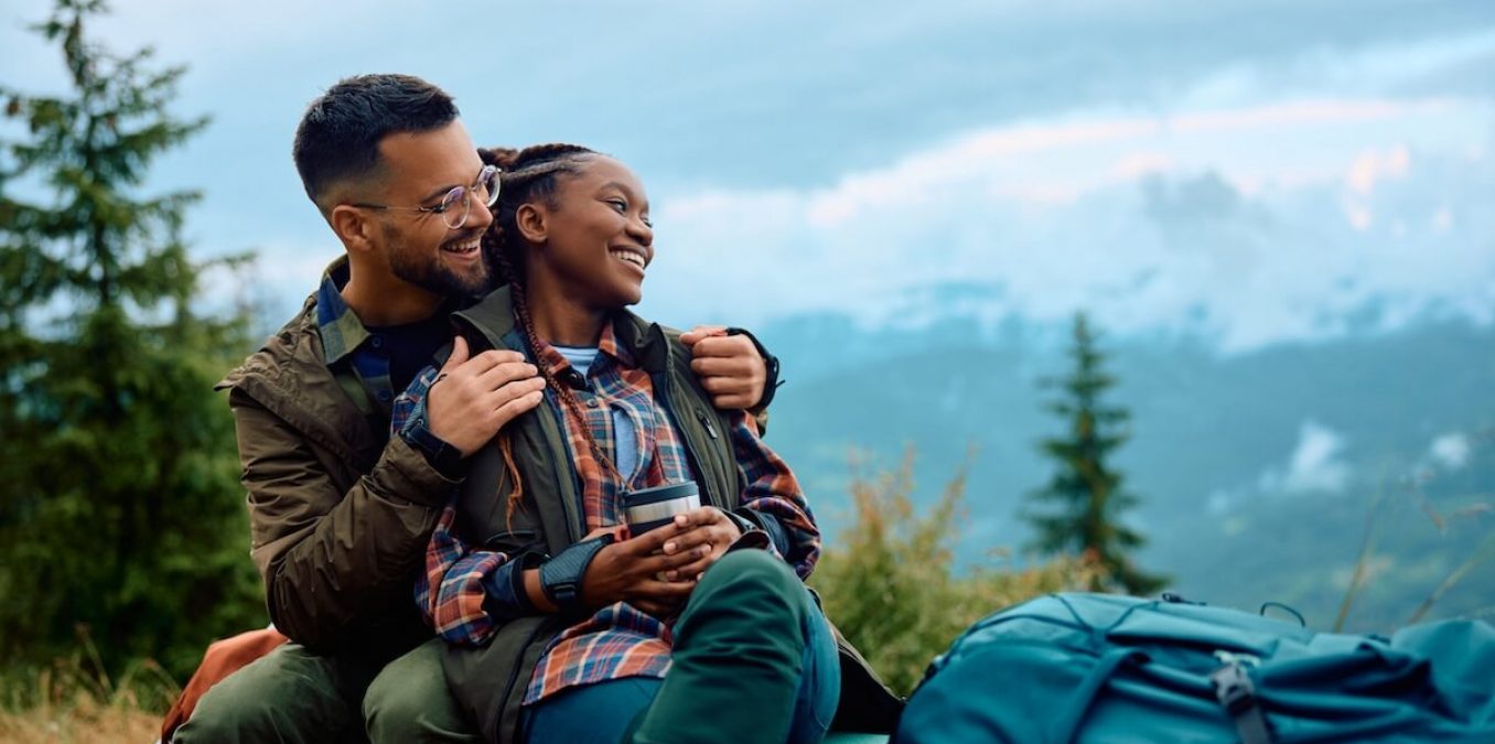 Carefree couple enjoys in view while taking break during hiking in nature.