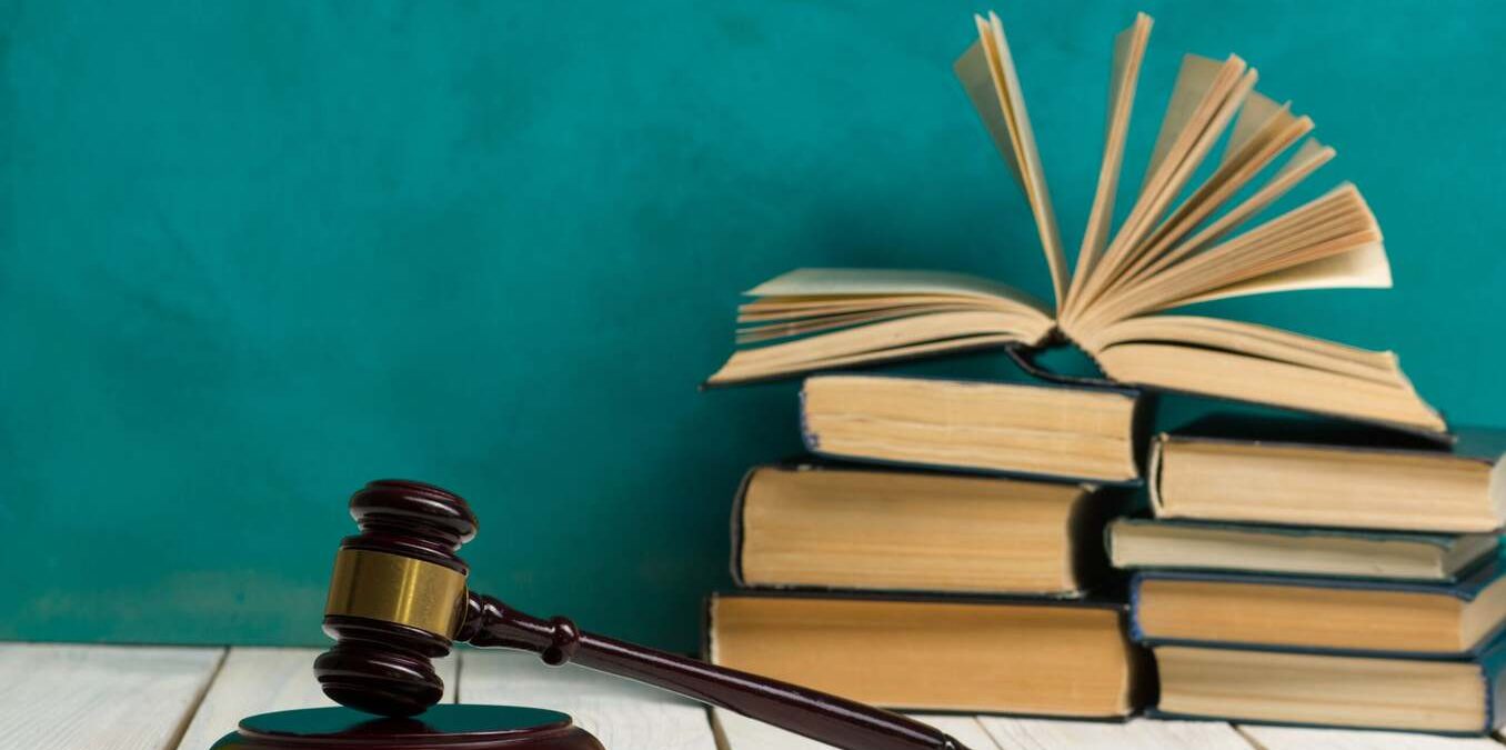 Law concept - Open law book with a wooden judges gavel on table in a courtroom or law enforcement office on blue background