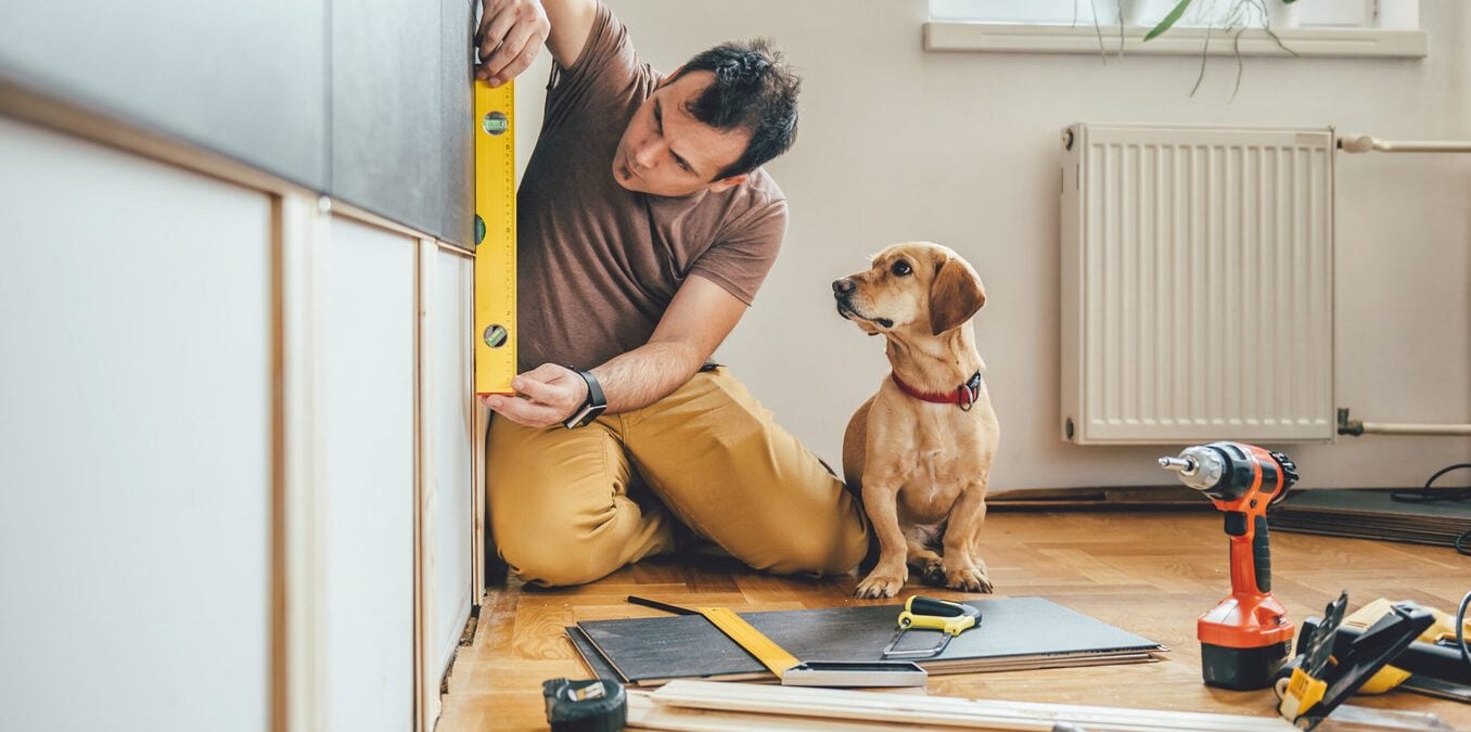 Man doing renovation work at home together with his small dog