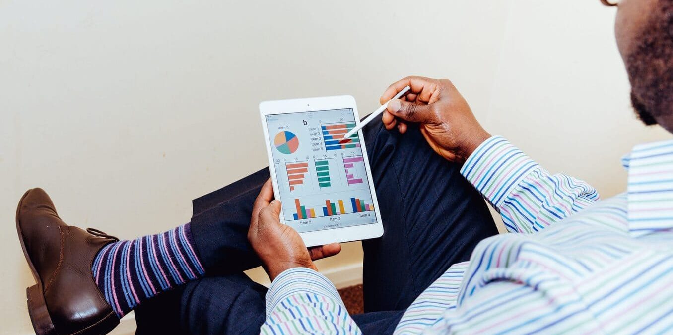 A man reviews some charts and graphs on an iPad