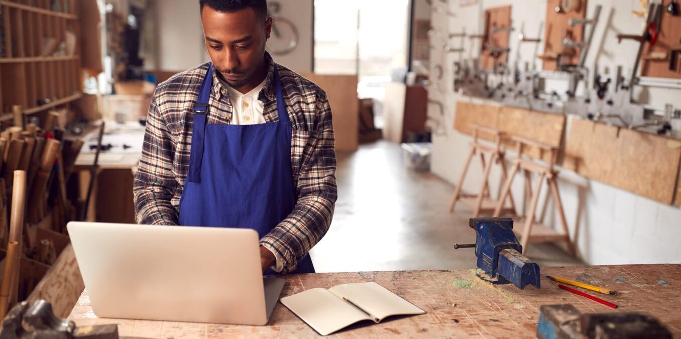Man working on his laptop in a woodworking studio
