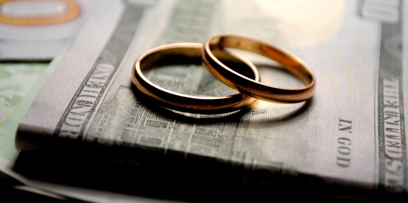 wedding rings on top of a stack of dollars