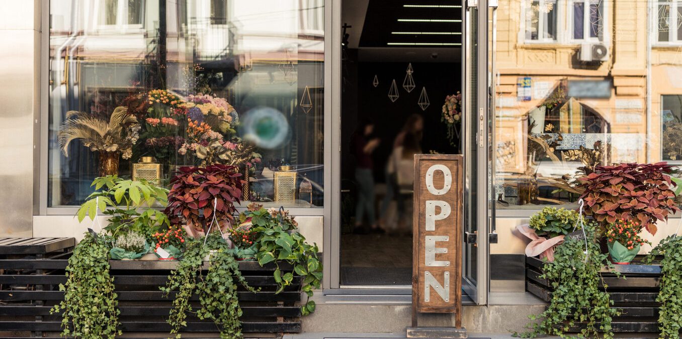 open signboard, potted plants and reflecting windows at flower shop