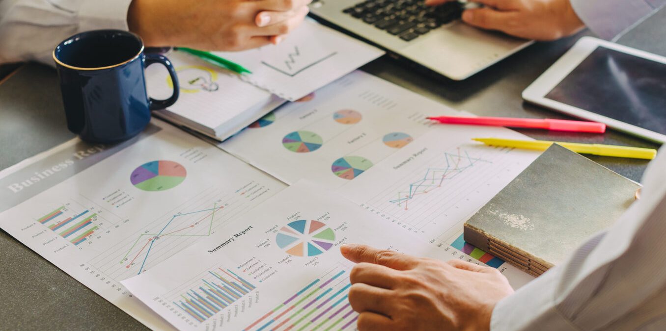 Two businessman investment consultant analyzing company financial report balance sheet statement working with documents graphs