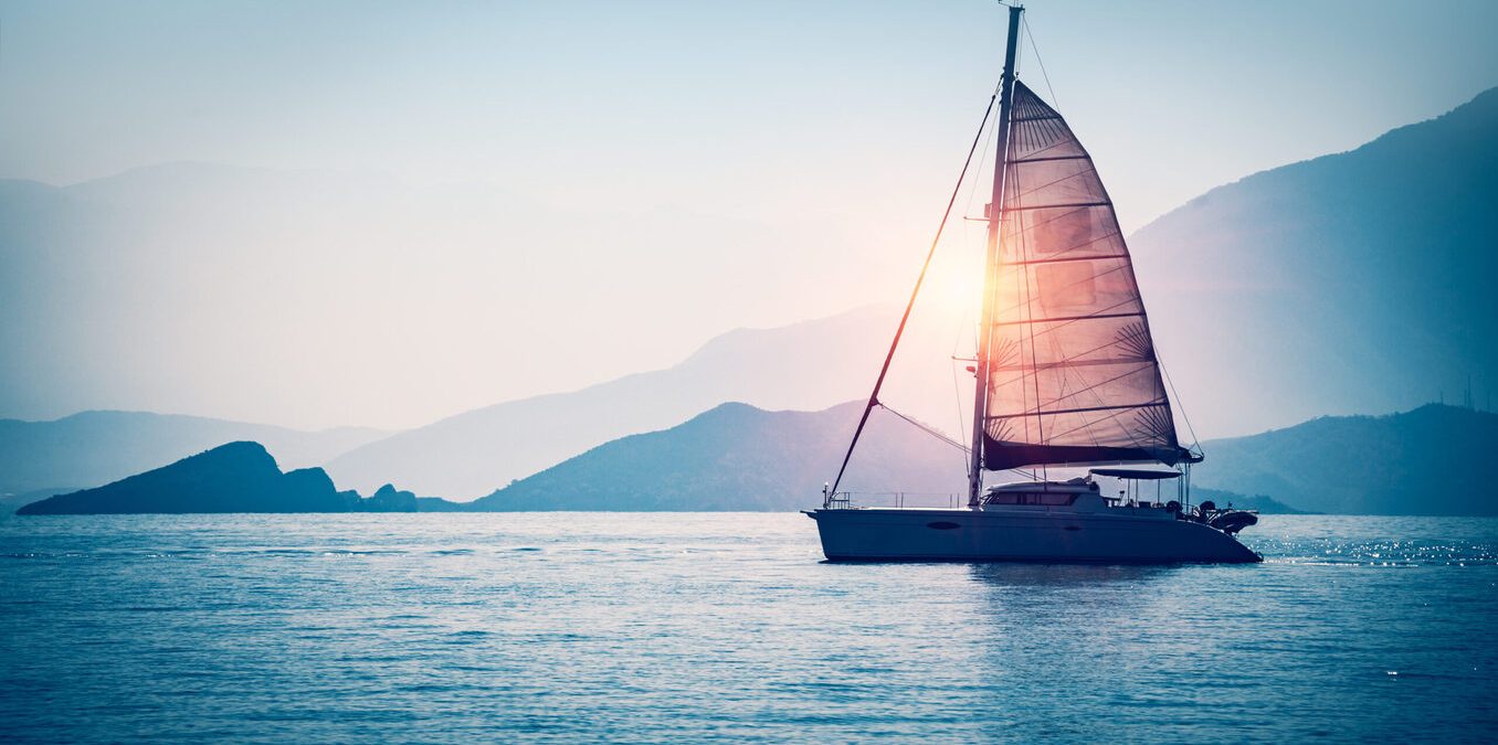 Banner 3:1. Sailboat in the sea in the evening sunlight over sky background. Luxury summer adventure or active vacation concept.