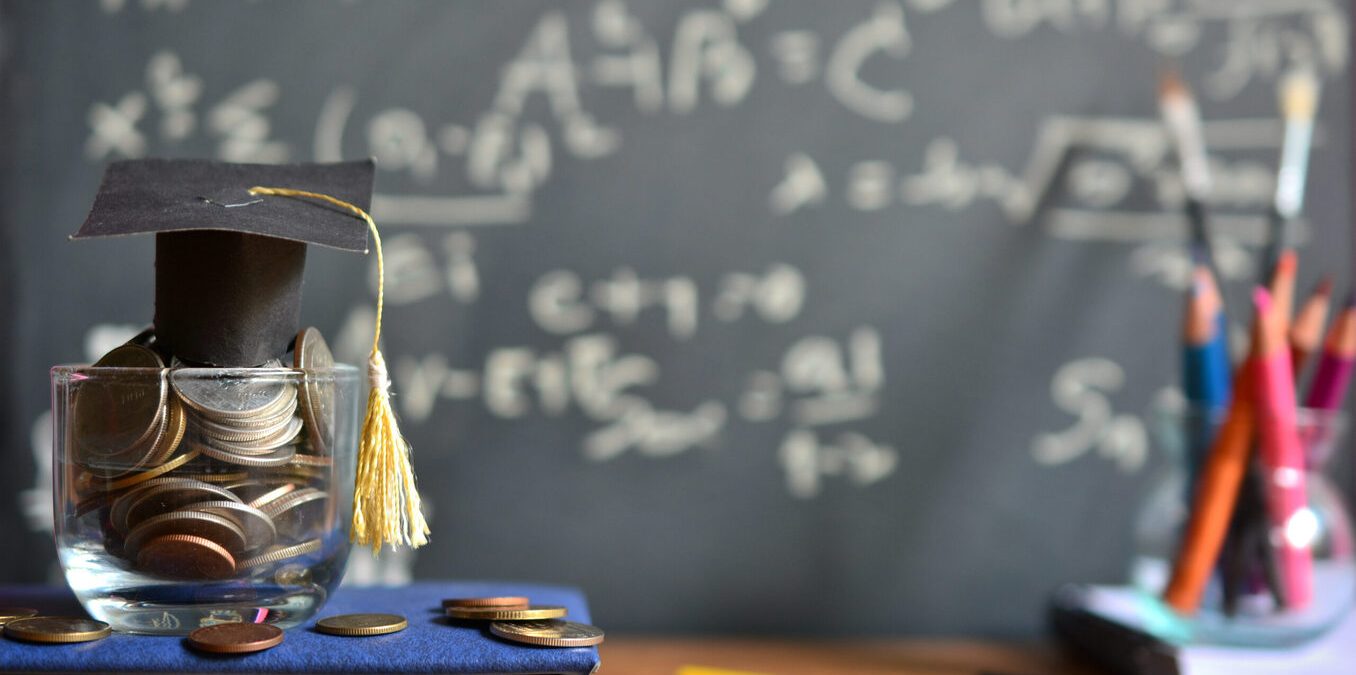 Scholarship concept. Coins, dollar banknotes and graduation cap on wooden table