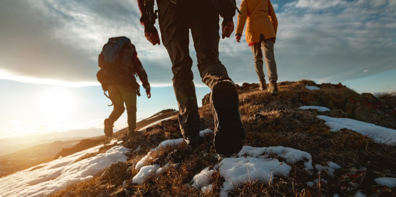 Small,Group,Of,Tourists,Walks,At,Mountain,Top,At,Sunset