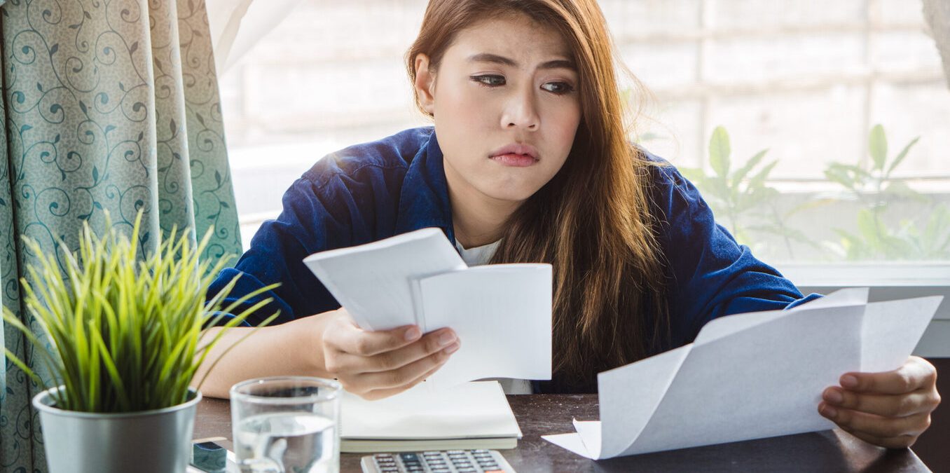 stressed young asian woman trying to find money to pay credit card debt
