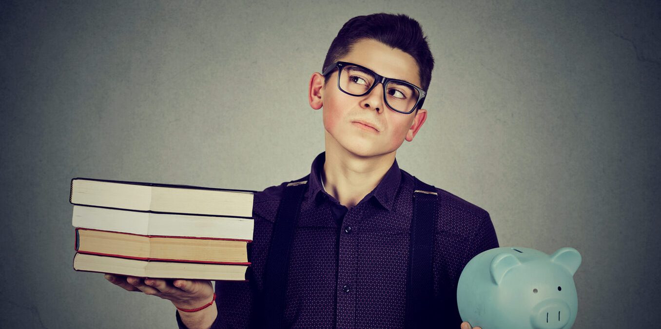Young man with stack pile of books and piggy bank full of debt rethinking future career path