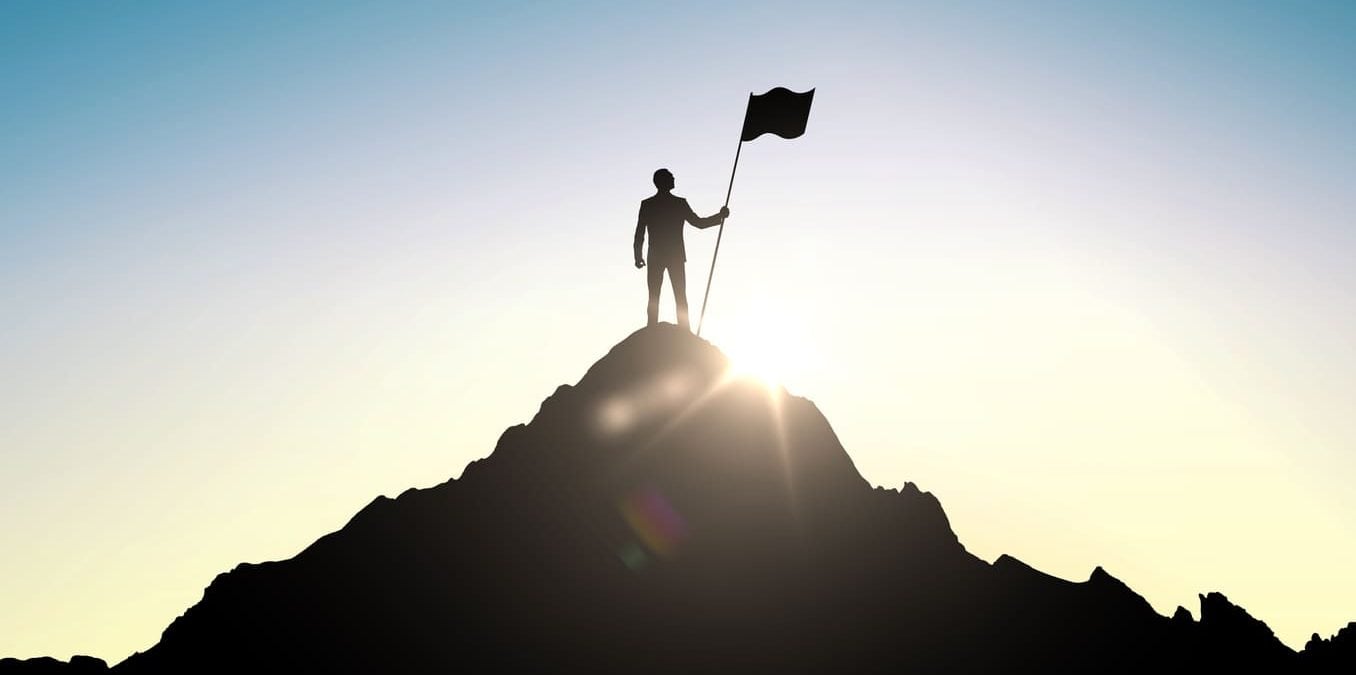 Success and achievement concept , silhouette of businessman with flag on mountain top