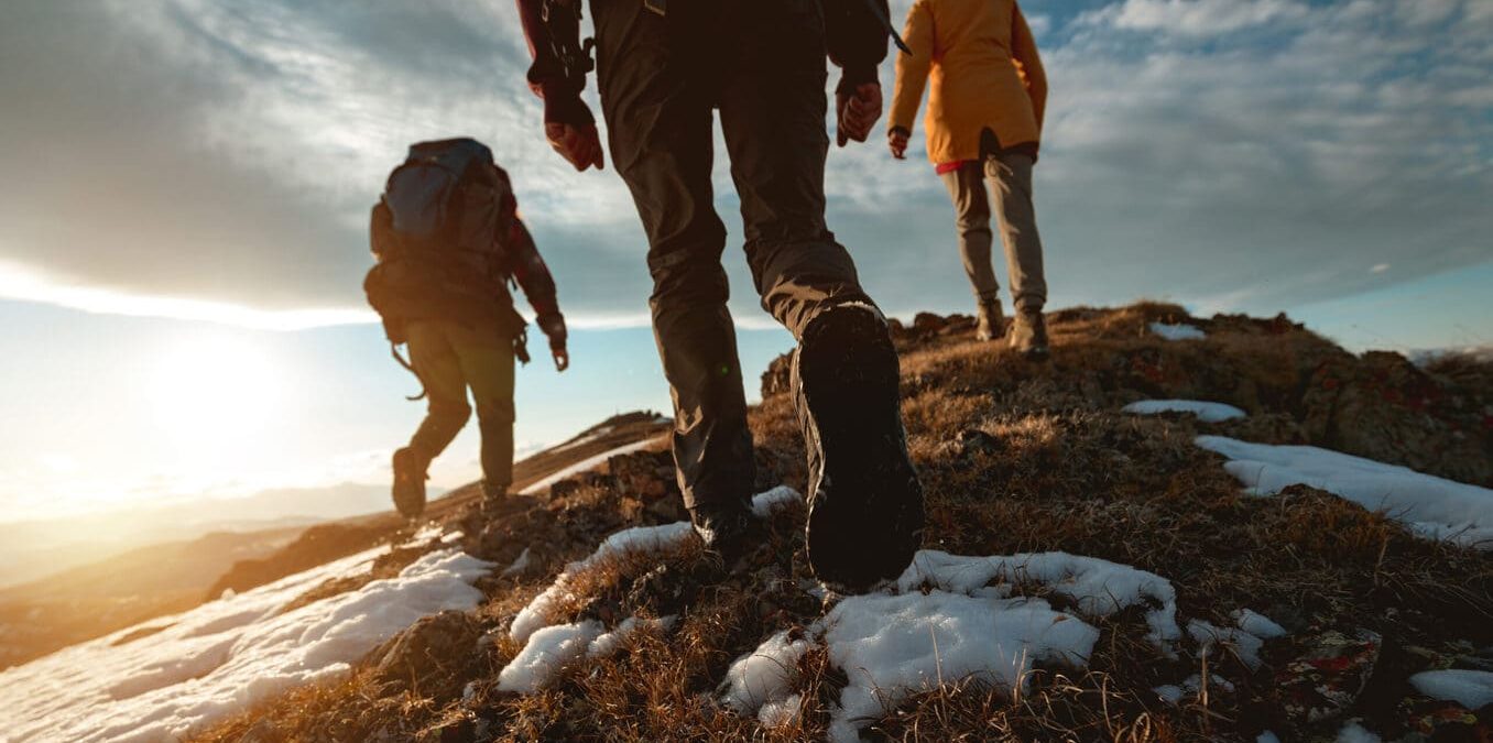 Small group of tourists walks at mountain top at sunset time. Close up photo