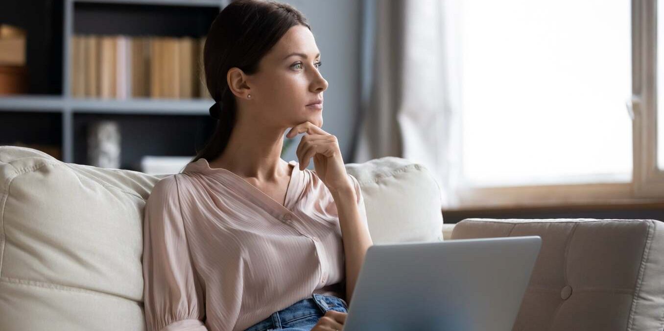 Woman contemplating in front of laptop on the couch