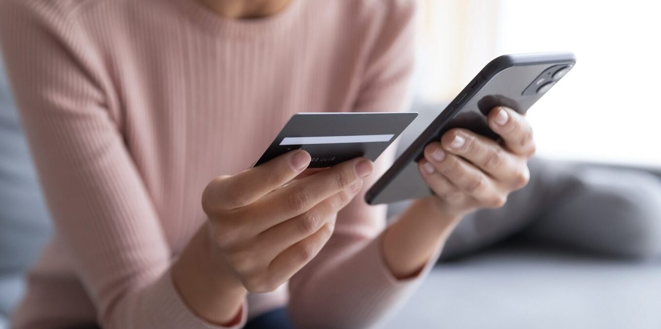 Woman holding a credit card and entering bank info in her phone