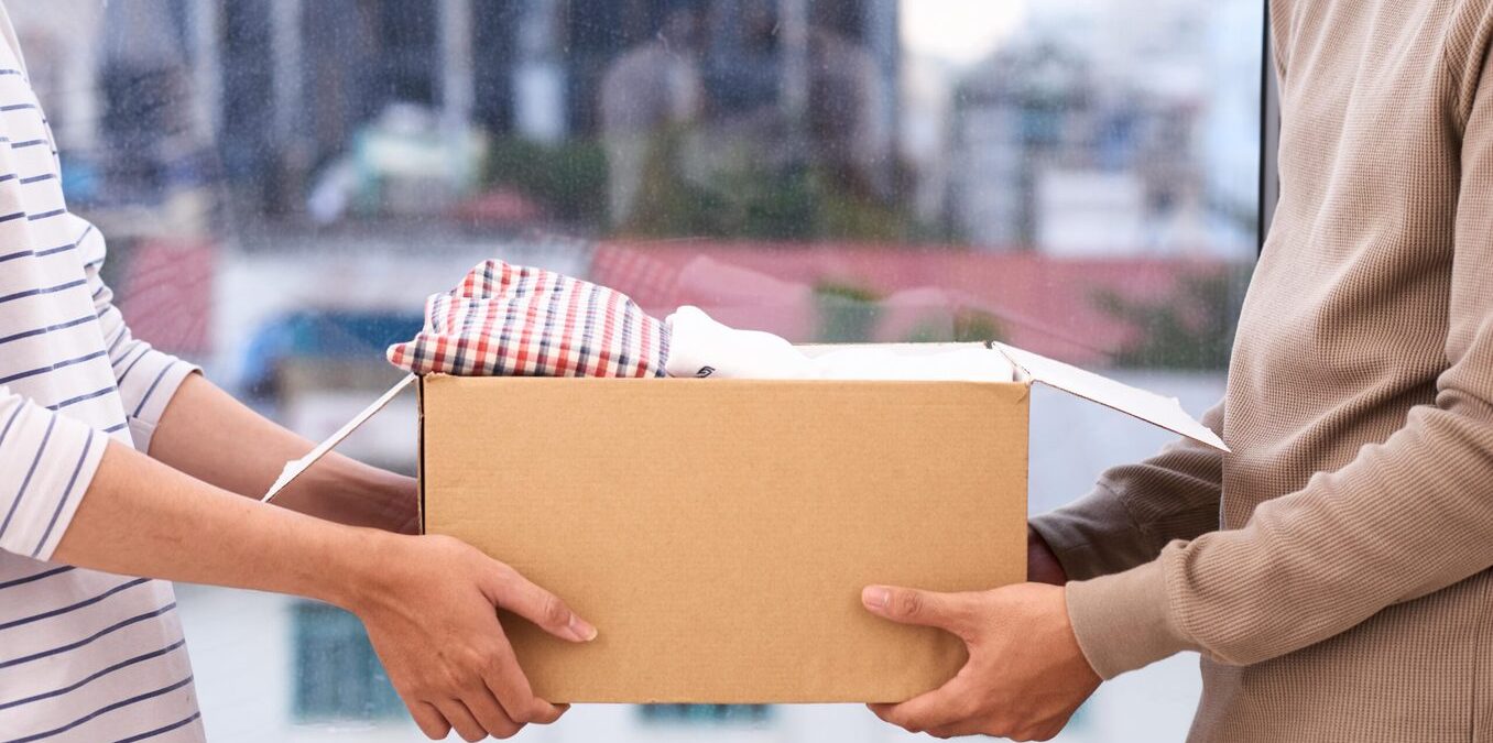Woman handing box to man. Cityscape in the background