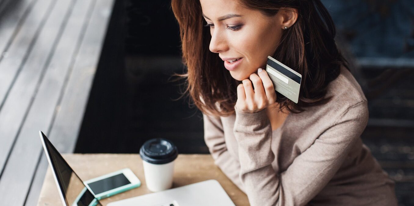 Woman holding a credit card while using a laptop
