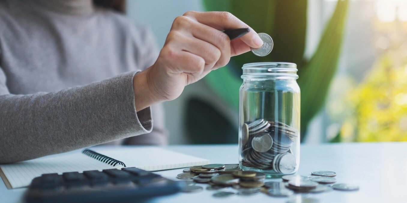 A closeup of a woman inserting coins into a jar