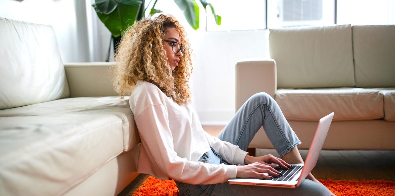 Woman sitting on the floor with her laptop in a living room