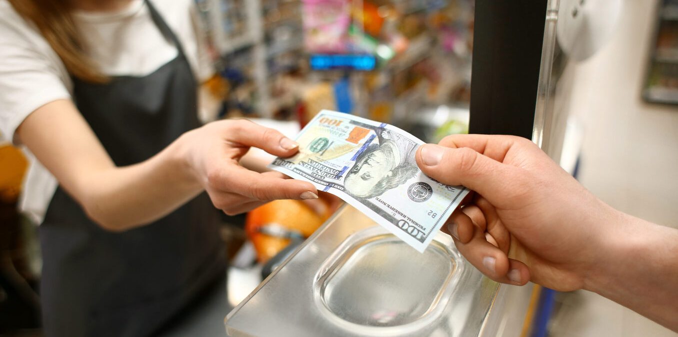 Young man paying for goods in supermarket, closeup