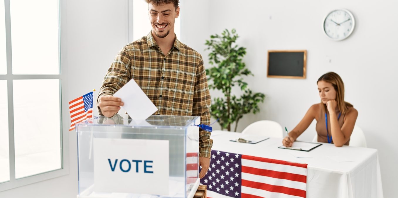 Young American voter putting vote in ballot box